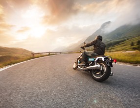 Mann, der in den Bergen Motorrad fährt – Symbolbild für eine Kfz-Versicherung für Motorradfahrer